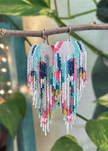 Colorful beaded earrings hanging on a branch with a blurred green background