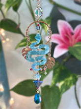 Decorative hanging ornament with blue glass pieces and beads against a floral background